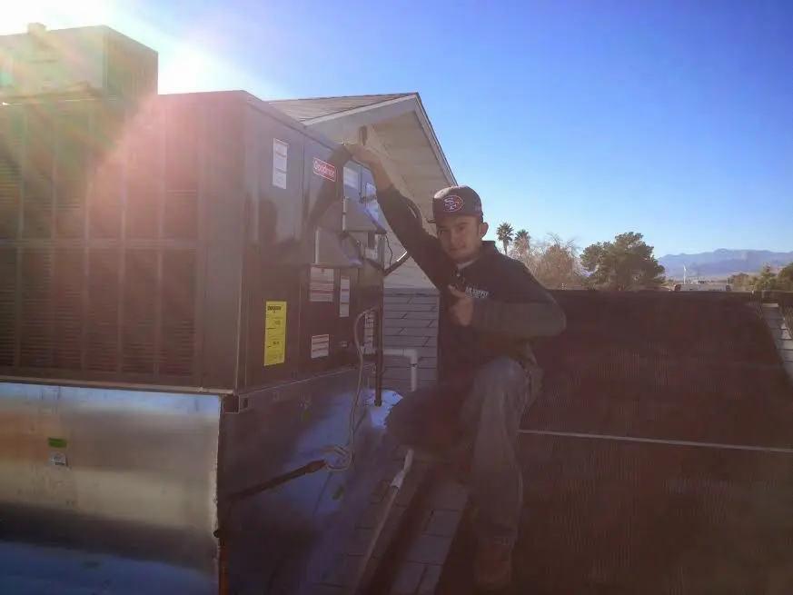HVAC technician performing Air Duct Cleaning on a rooftop unit in Bloomingdale